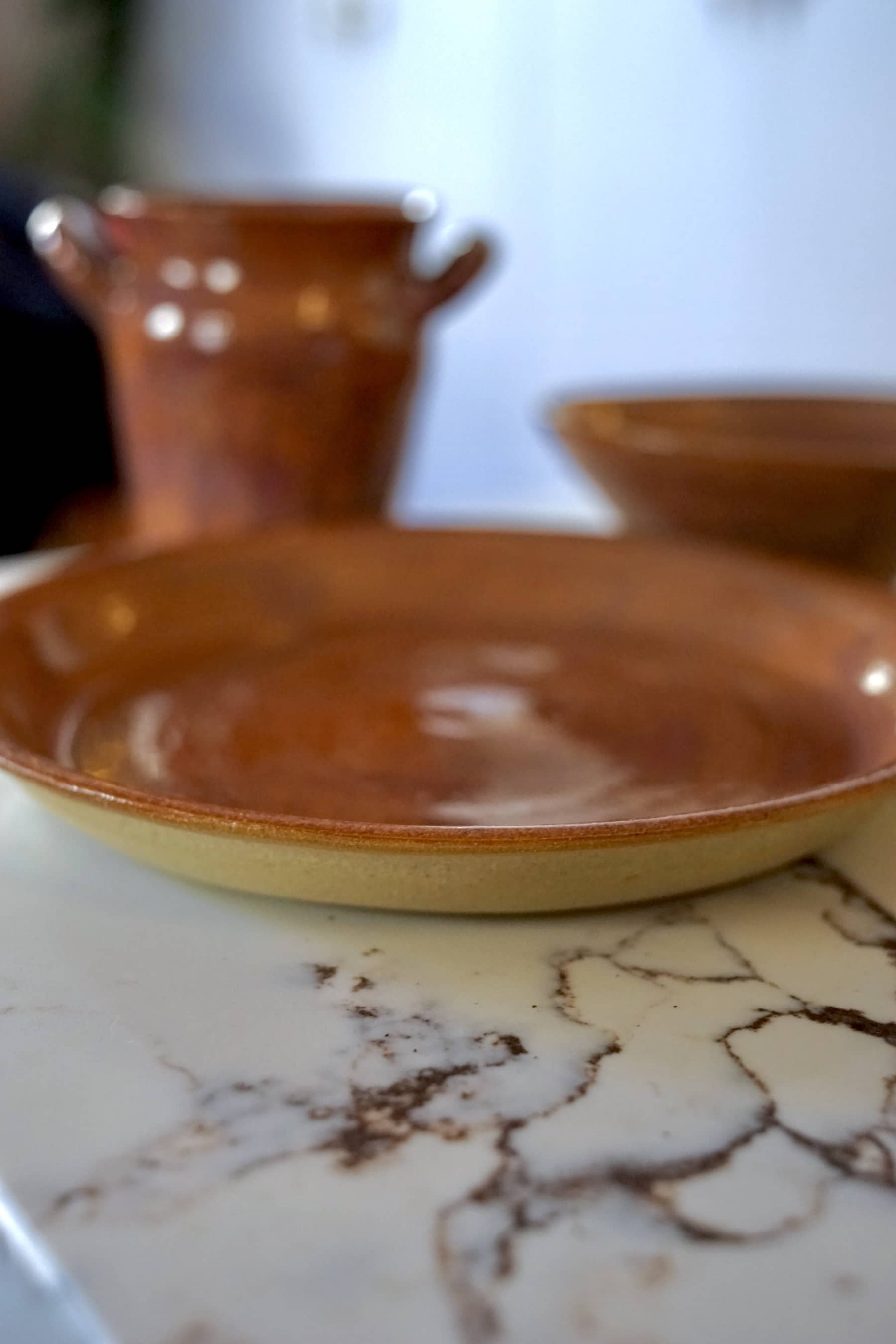 Amber glazed dinner plate with shallow bowl, close-up view.