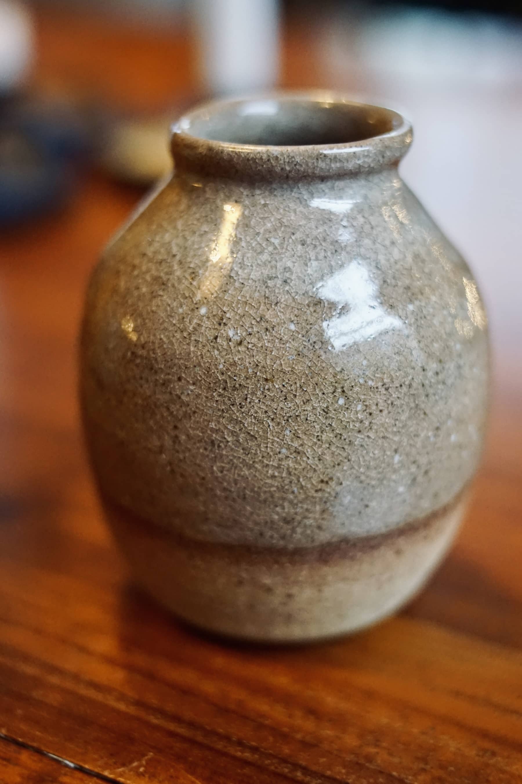 Close-up detail of crazed crackle glaze texture on amber ceramic bud vase.