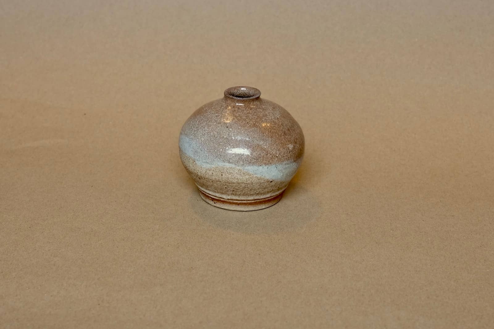Miniature rounded bud vase with dual-toned glaze.