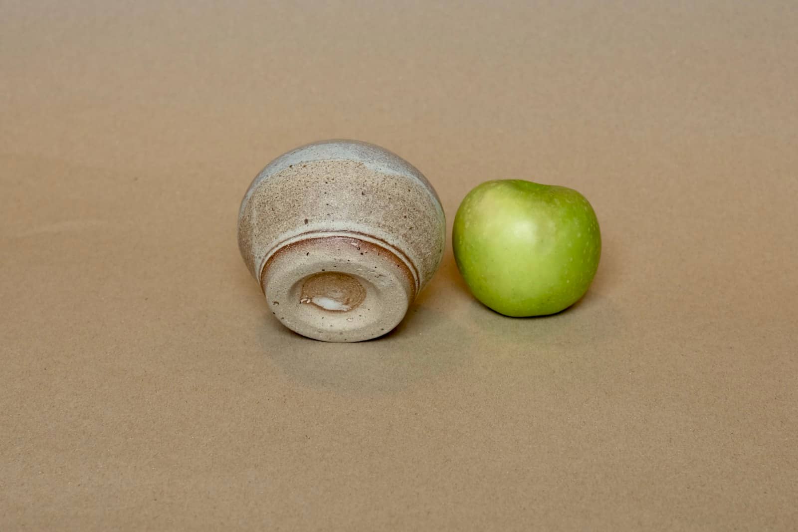 Small bud vase showing warm brown and pale grey-blue glaze.