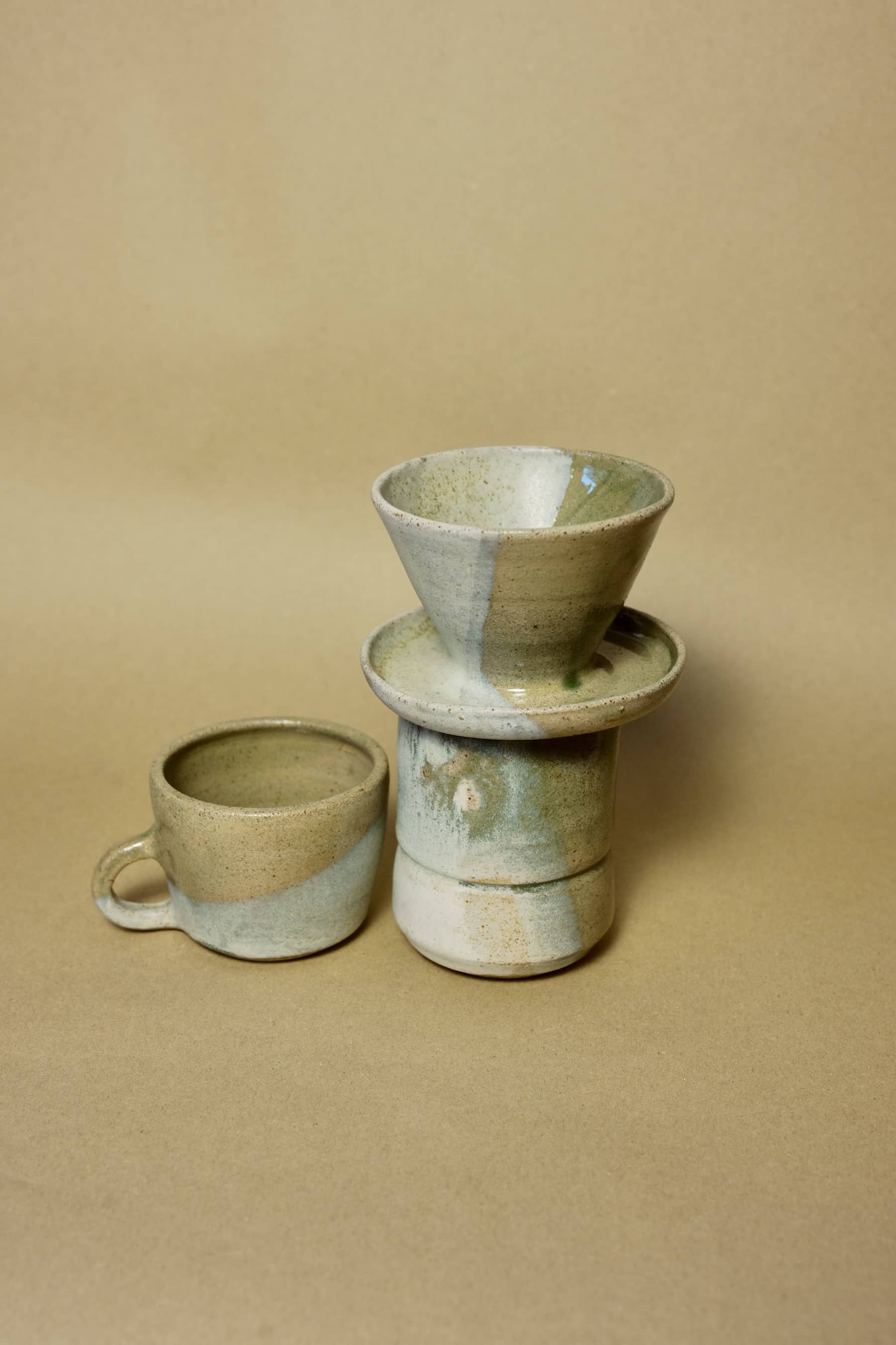 Handmade ceramic coffee pour-over set with funnel dripper and carafe in a matte sage green and cream split-glaze finish.
