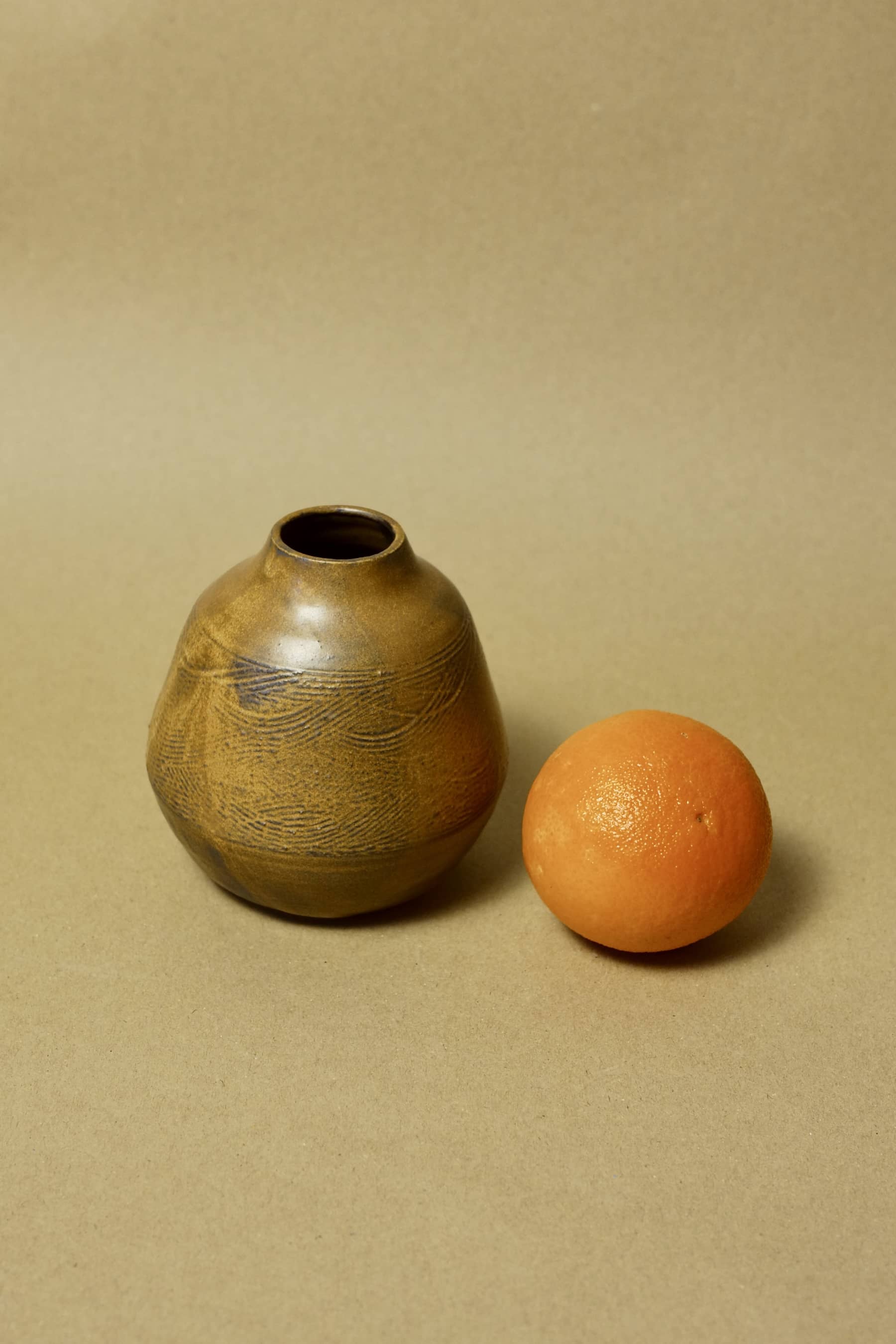 Hand-etched wave pattern bud vase in toasted ochre clay, side view.