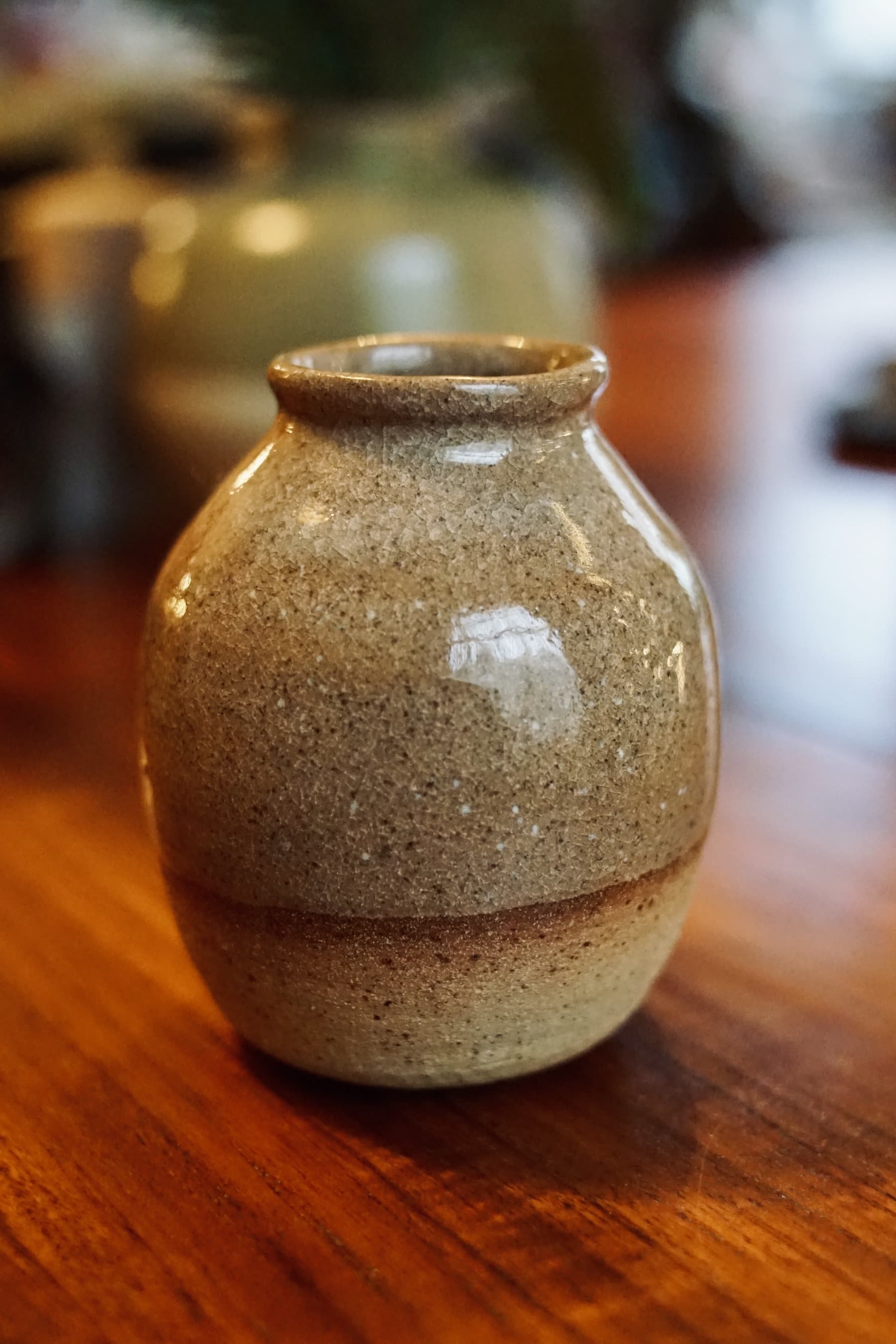 High-gloss amber ceramic bud vase with a specialized crazed crackle glaze finish on a wooden tabletop.