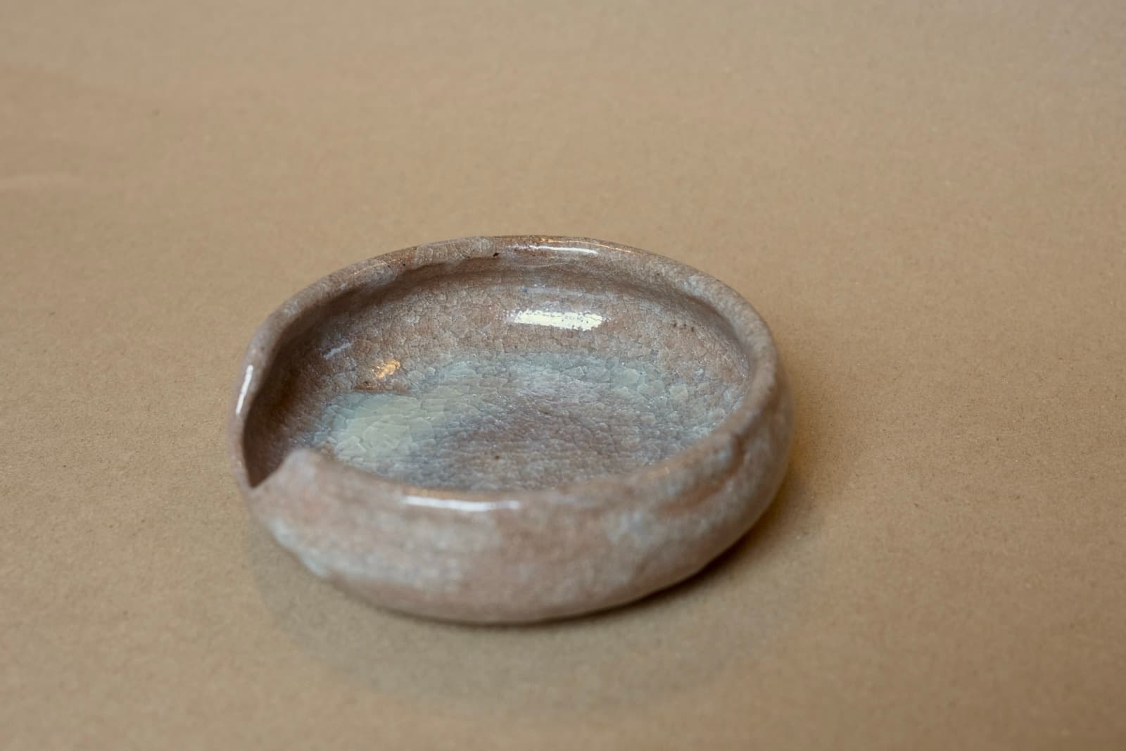 Small shallow dish with soft grey-blue glaze and natural brown clay showing through.