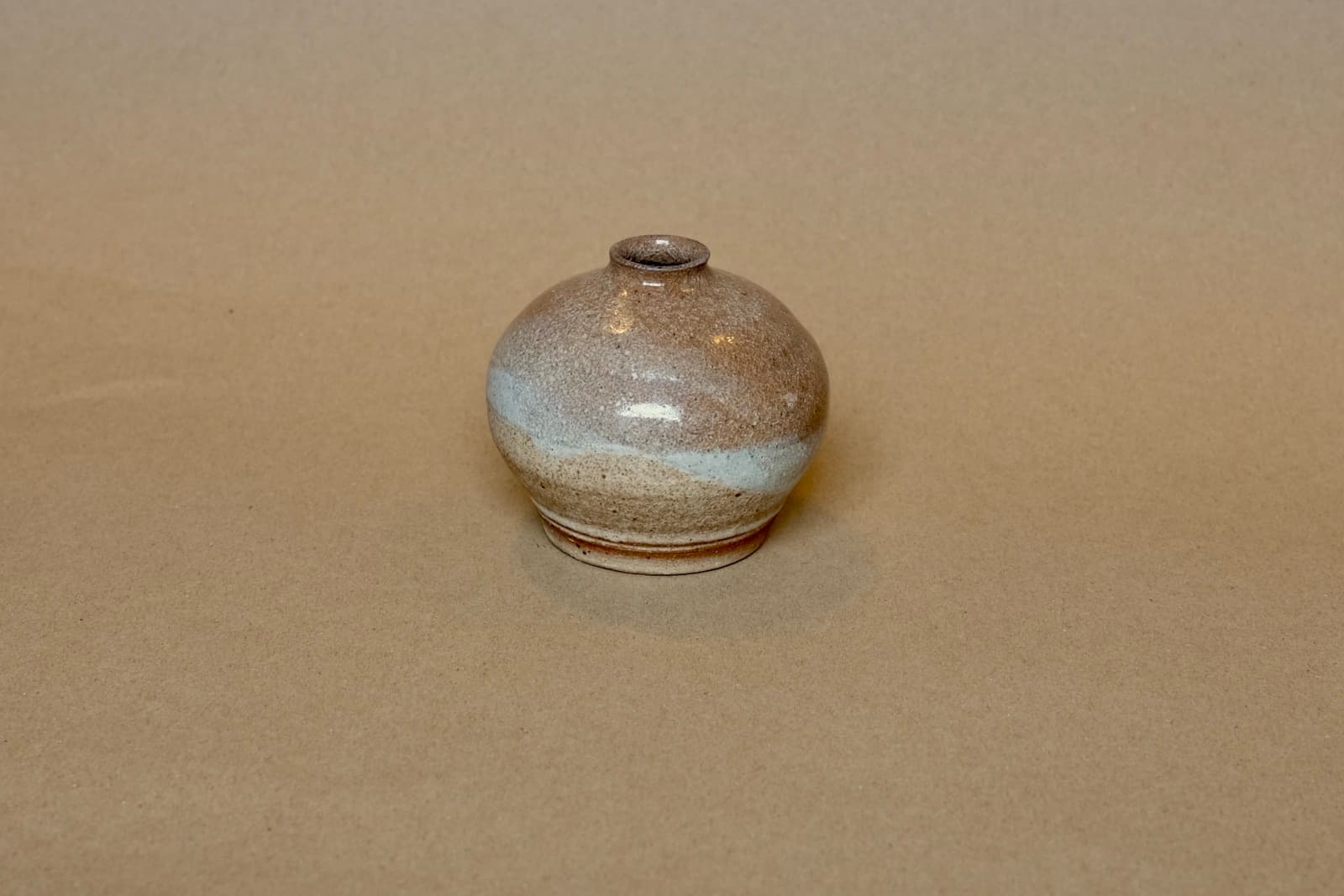 Miniature rounded bud vase with dual-toned glaze.