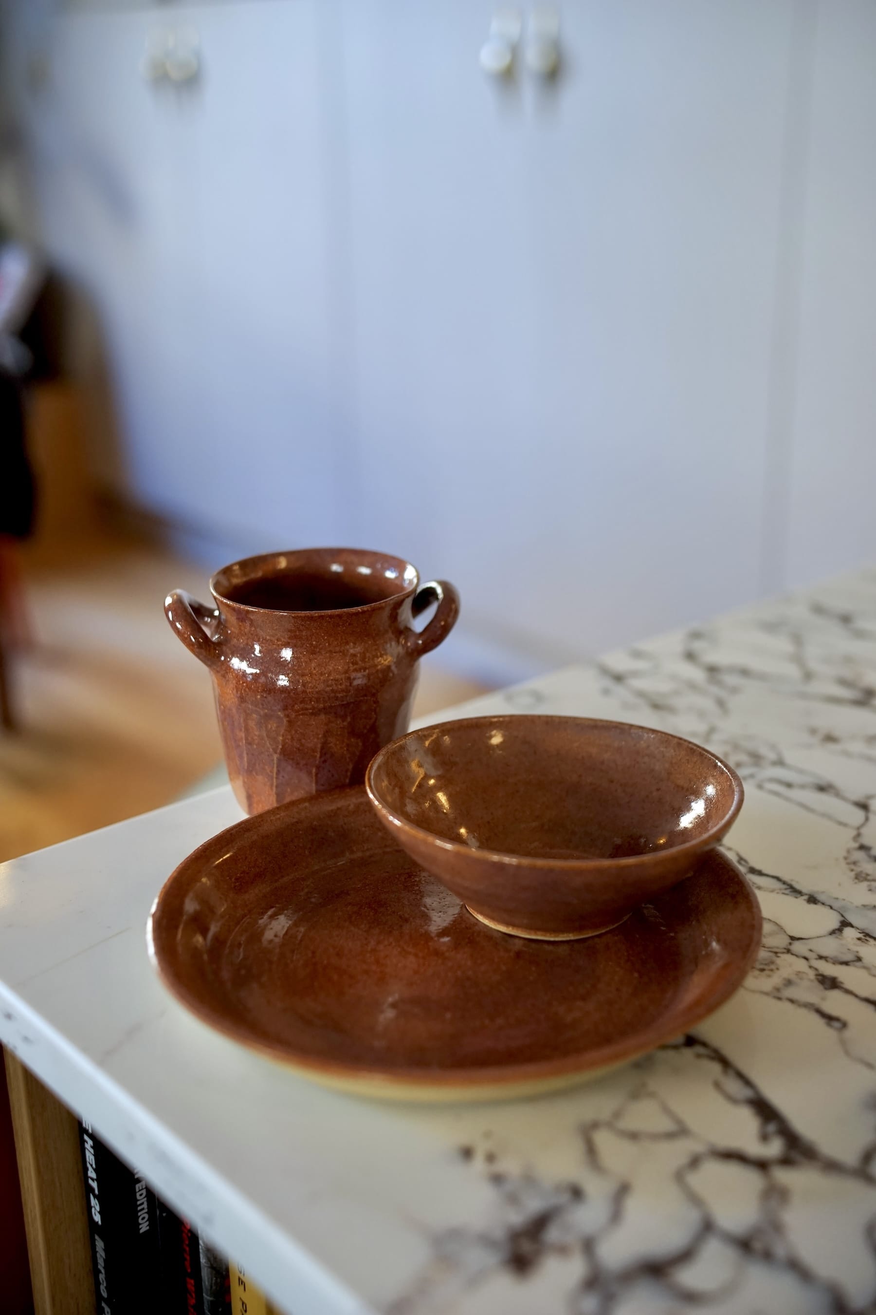 Coordinated amber glazed dinner set featuring a dinner plate and shallow bowl on a white marble surface.