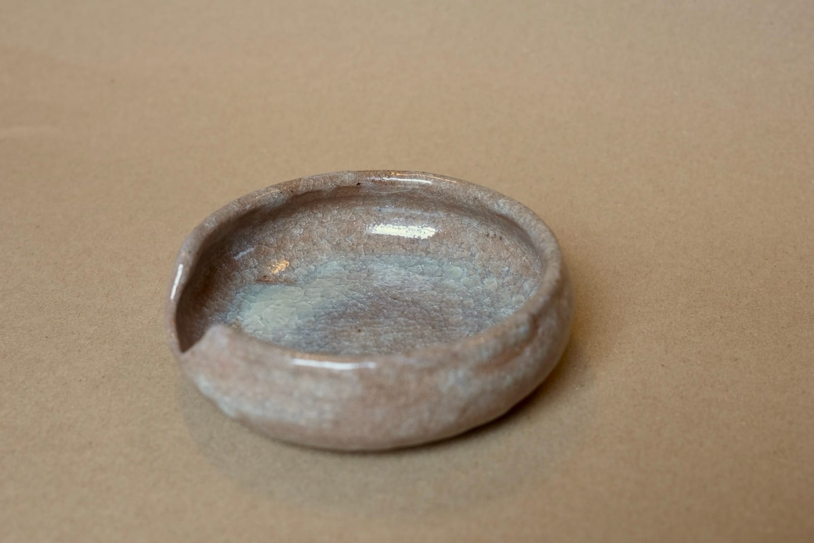 Small shallow dish with soft grey-blue glaze and natural brown clay showing through.